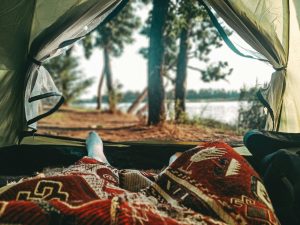 person laying down in tent with doors open view of the wilderness