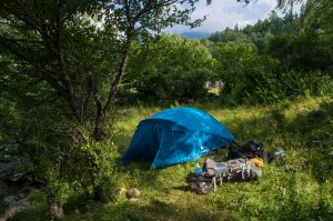 blue tent pitched alone in green grass field. 