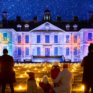 large stately home covering whole of the photo background. Large colourful snowfalls project onto walls and floor bis filled with yellow light's. 